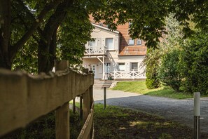 A building with a front porch, a staircase leading to the entrance, and a gravel driveway.