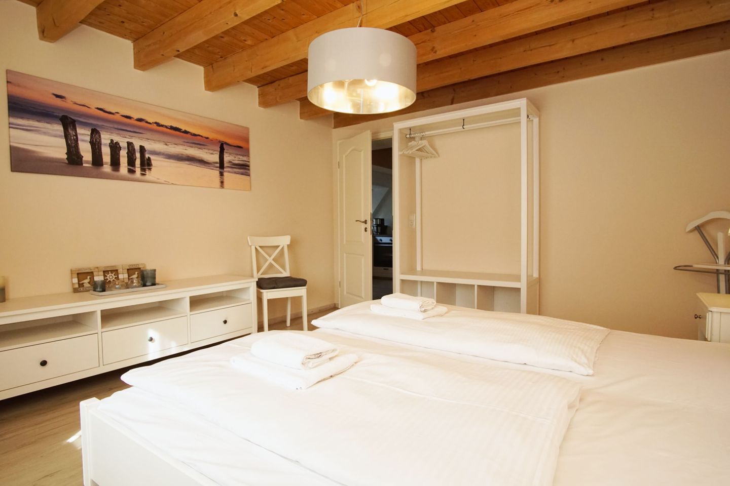 A bedroom with a large bed, a chair, a desk, and a wardrobe.