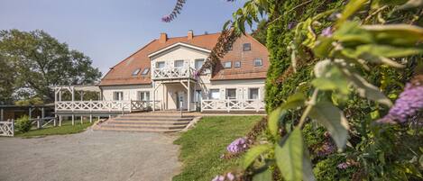 Ein zweistöckiges Haus mit Balkon, Eingang und gepflasterter Auffahrt.