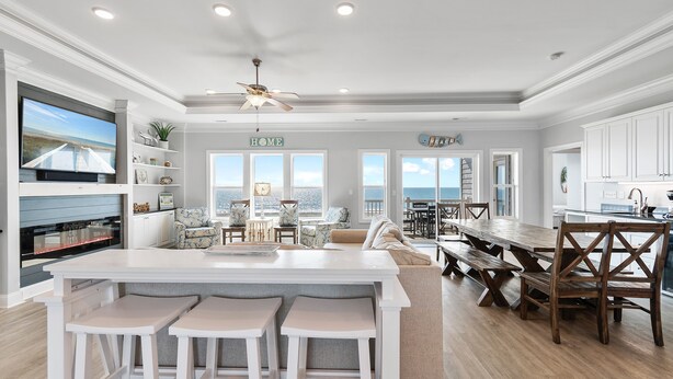 A spacious kitchen with a central island, bar stools, and a view of the ocean through large windows. - Isle Oasis. Oceanfront. Elevator, Heatable Pool,  Drct Bch Access. Grt Location. (Holden Beach)