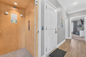 A hallway with wooden walls, a white door, and a grey carpet.