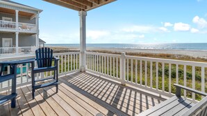 A wooden deck with a view of the beach, a chair, and a table. - Isle Oasis. Oceanfront. Elevator, Heatable Pool,  Drct Bch Access. Grt Location. (Holden Beach)