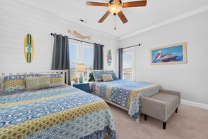 A bedroom with two beds, a ceiling fan, and a painting of a pelican.