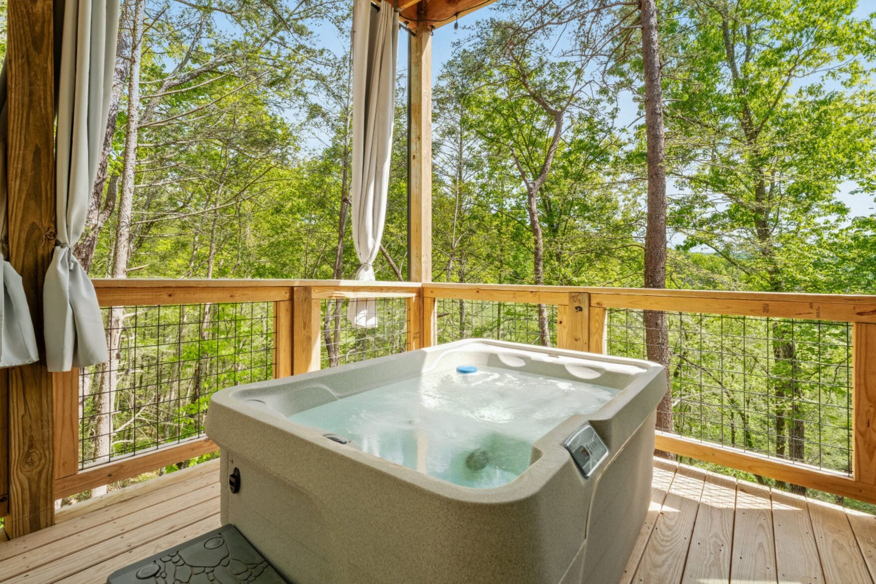 A hot tub on a wooden deck with a view of trees.