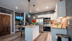 A modern kitchen with a central island, stainless steel appliances, and a wooden floor.