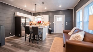 A modern kitchen with a central island, bar stools, and pendant lighting.
