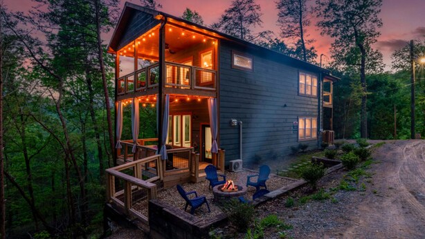 A cabin with a deck, outdoor seating, and a fire pit.