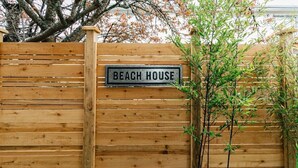 A wooden fence with a sign that reads "BEACH HOUSE". - Lovely 2 bedroom suite steps from The beach (Victoria)
