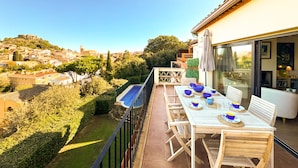 A balcony with a table set for dining, overlooking a cityscape with buildings and greenery.