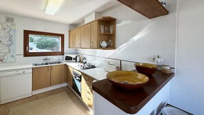 A modern kitchen with wooden cabinets, a microwave, a stove, and a large island with a bowl.