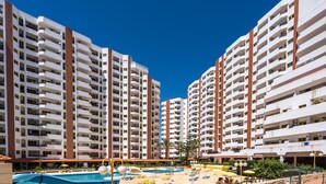 A hotel with multiple high-rise buildings, a swimming pool, and sun loungers. - #150 Praia da Rocha by Home Holidays (Portimão)