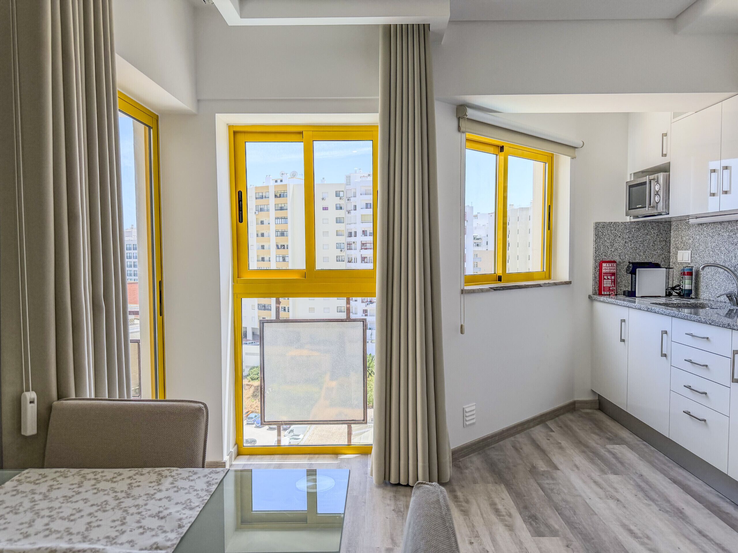 Una cocina moderna con comedor, ventanas amplias y vista a edificios.