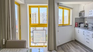 A modern kitchen with a dining area, large windows, and a view of buildings. - #150 Praia da Rocha by Home Holidays (Portimão)