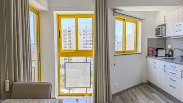 Una cocina moderna con comedor, ventanas amplias y vista a edificios.