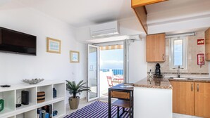 Eine moderne Küche mit Flachbildfernseher, offenen Regalen und Blick ins Freie.