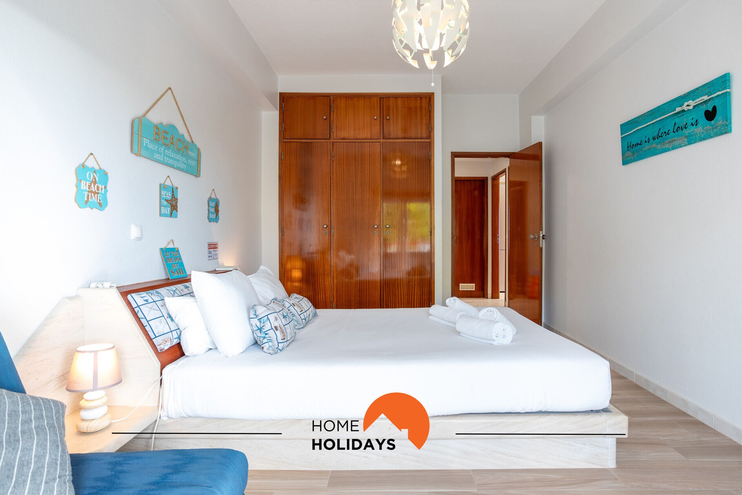 A bedroom with a bed, bedside table, lamp, and wall decorations.