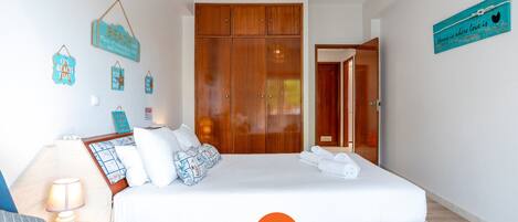 A bedroom with a bed, bedside table, lamp, and wall decorations.