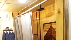 Une salle de bain en bois avec un rideau de douche, un porte-serviettes avec des serviettes et un sol à motifs.