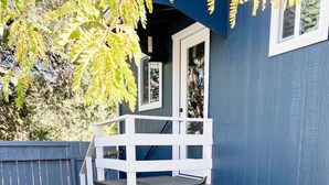 A patio with wicker furniture, a white deck, and a blue building in the background. - Near Downtown, Convenient to Restaurants, 2 Cruiser Bikes To Explore With! (Prescott)