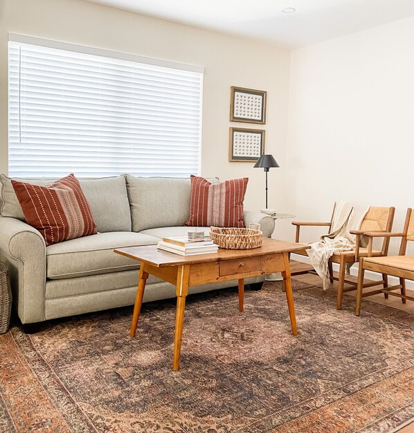 A living room with a sofa, a coffee table, a lamp, and a patterned rug.