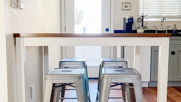 A kitchen with a white countertop, two metal stools, a window with blinds, and a door. - Near Downtown, Convenient to Restaurants, 2 Cruiser Bikes To Explore With! (Prescott)