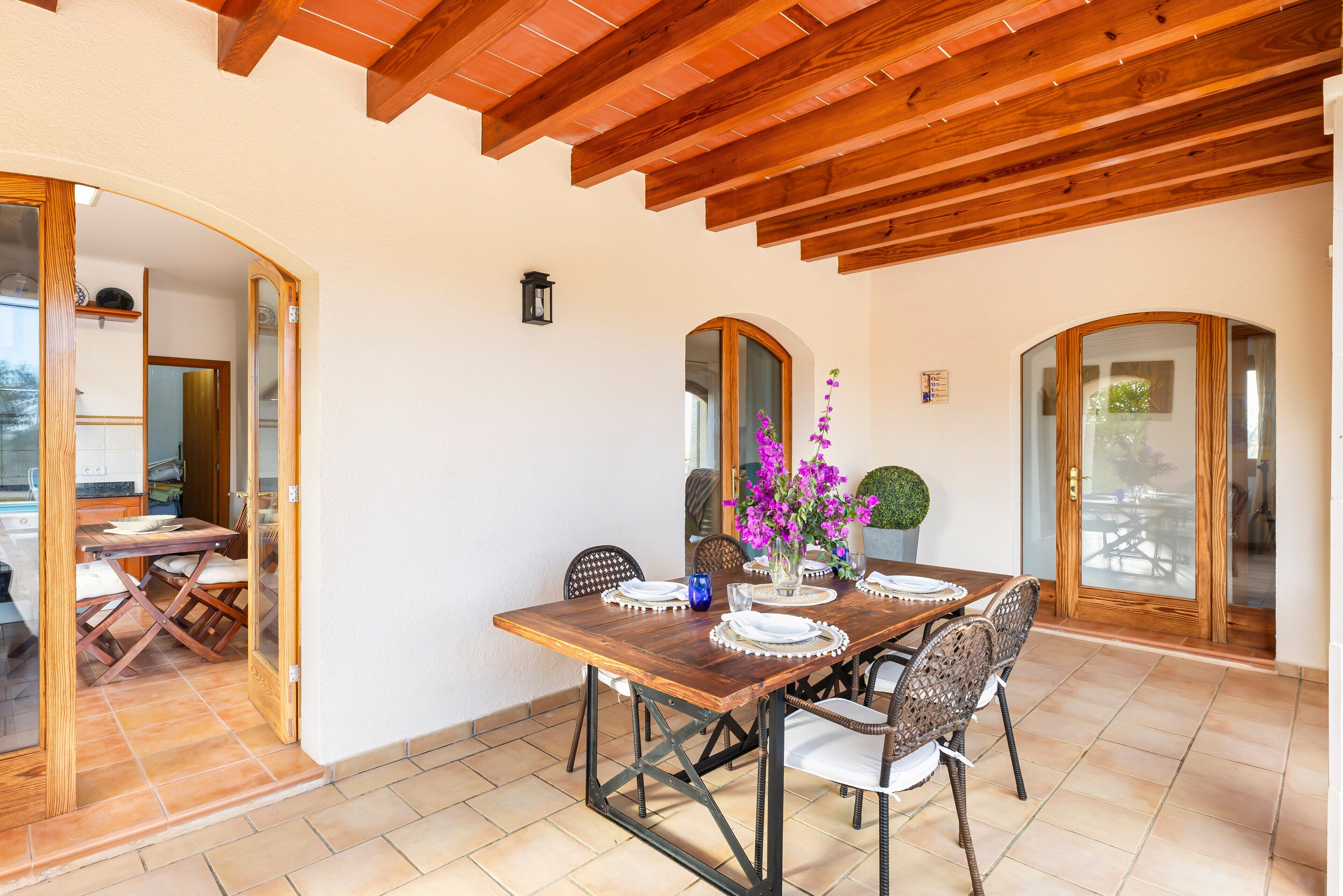 Un comedor con una mesa de madera, sillas y un jarrón de flores.
