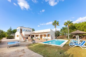 Uma casa moderna com piscina, espreguiçadeiras e um alpendre coberto.