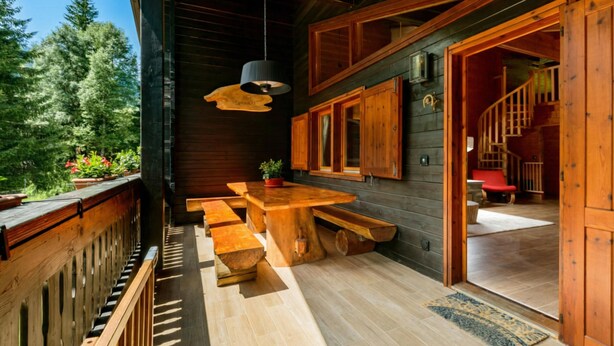 A wooden cabin with a dining area, a staircase, and a view of the forest. - Chalet Soleada with Fireplace and Terrace for 5, Pian San Giacomo, Mesocco, Switzerland (Pian San Giacomo, Mesocco)