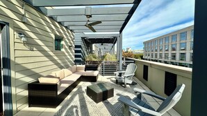 Un patio extérieur abrité, équipé d’un canapé, de fauteuils et d’un ventilateur de plafond.