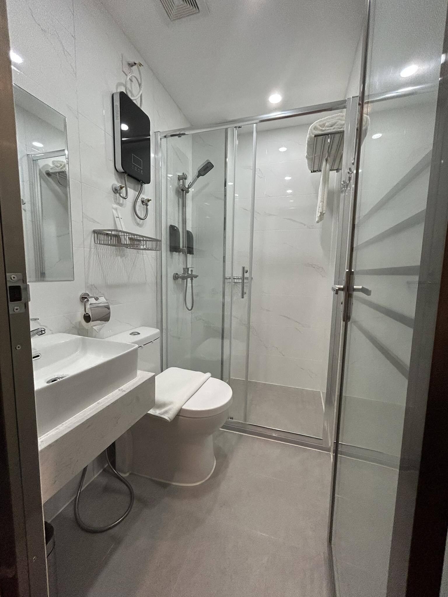 A modern bathroom with a glass-enclosed shower, a white sink, and a toilet.