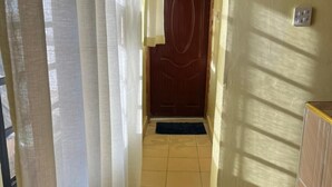 Um corredor com uma porta de madeira, um tapete azul escuro e piso de azulejos.