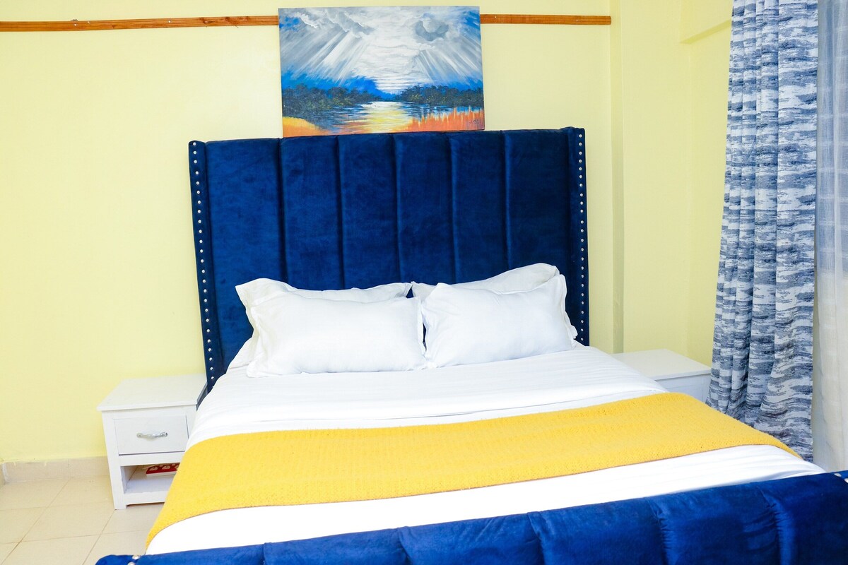 A bed with a blue headboard, white pillows, and a yellow blanket.
