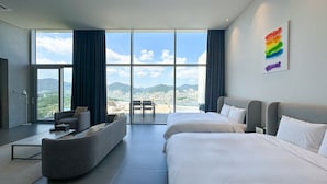 Habitación de hotel moderna con dos camas, un sofá y un amplio ventanal con vistas a la ciudad.
