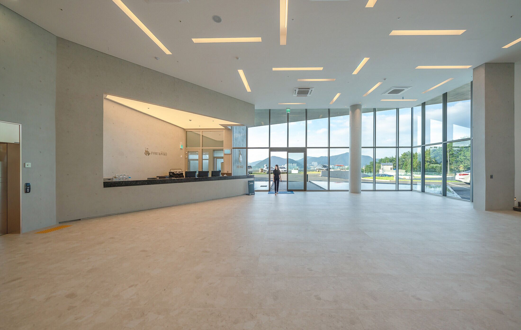 A spacious lobby with a reception desk, large windows, and a view of the outdoors.