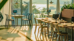 Un comedor moderno con ventanas amplias, mobiliario de madera y vistas al exterior.