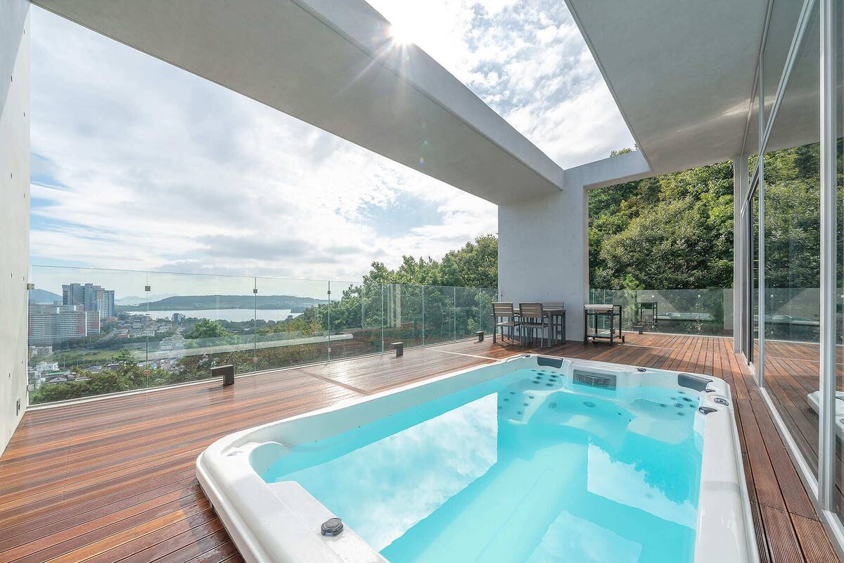 Un jacuzzi moderno al aire libre en una terraza de madera con vista a la ciudad.