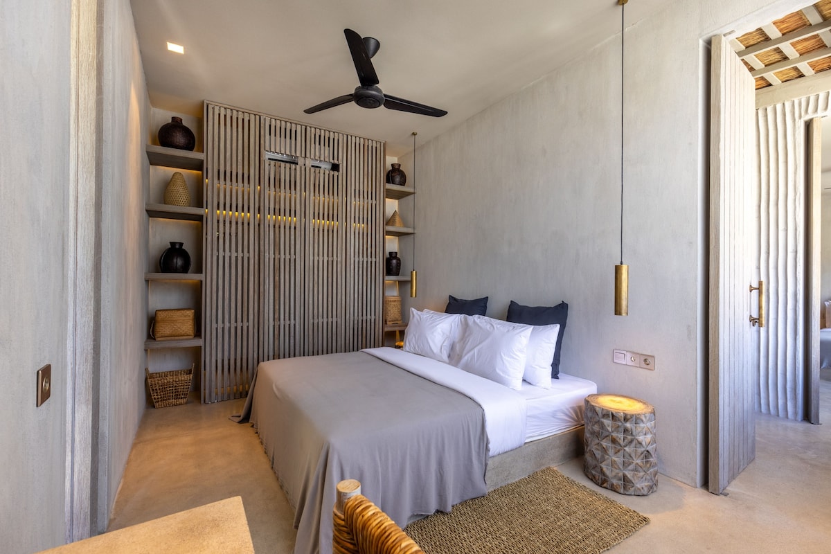 A bedroom with a bed, bedside tables, a ceiling fan, and a wardrobe with shelves.