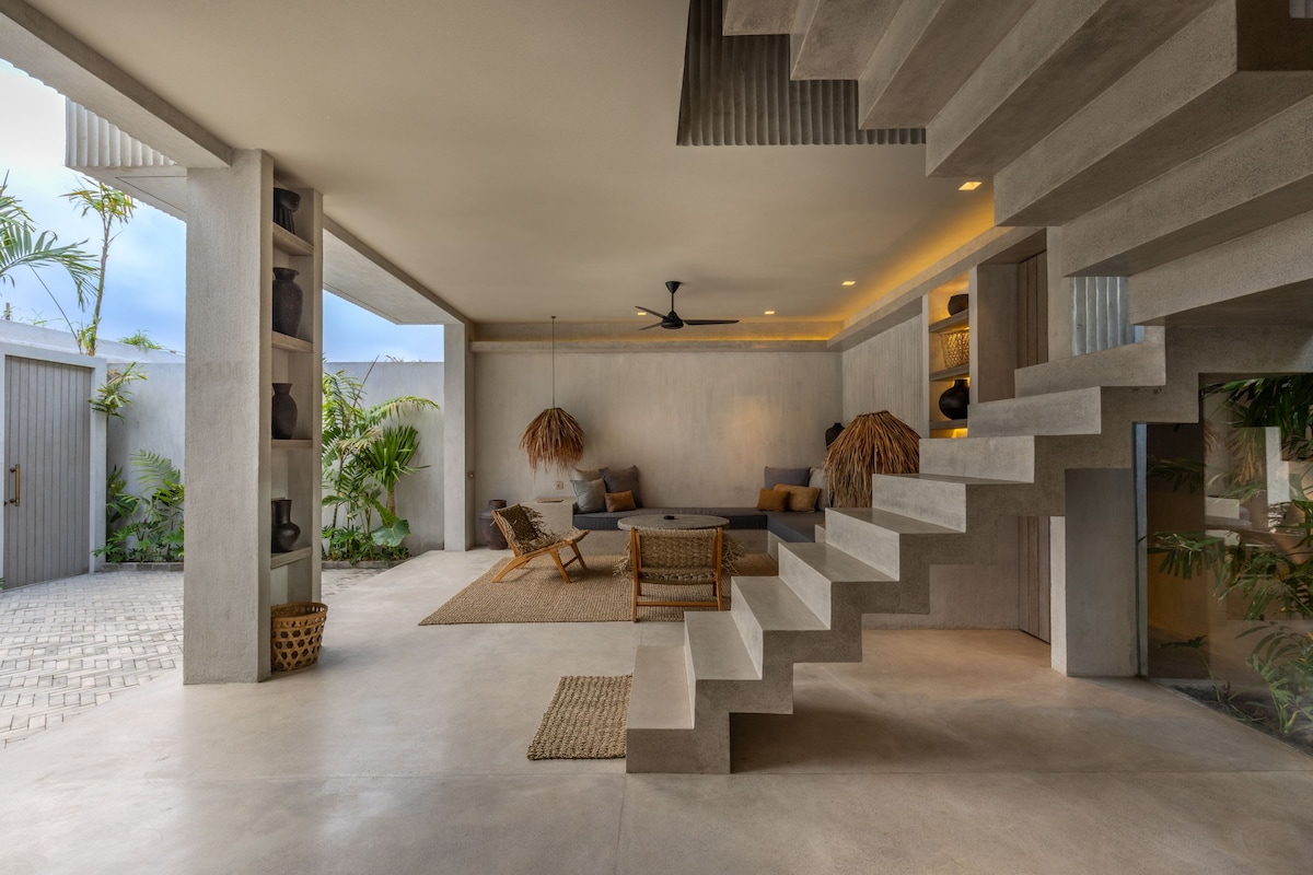 A modern interior with a staircase, seating area, and plants.