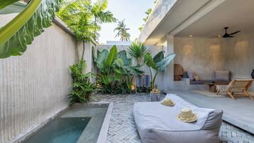 A modern outdoor living area with a pool, comfortable seating, and lush tropical plants.