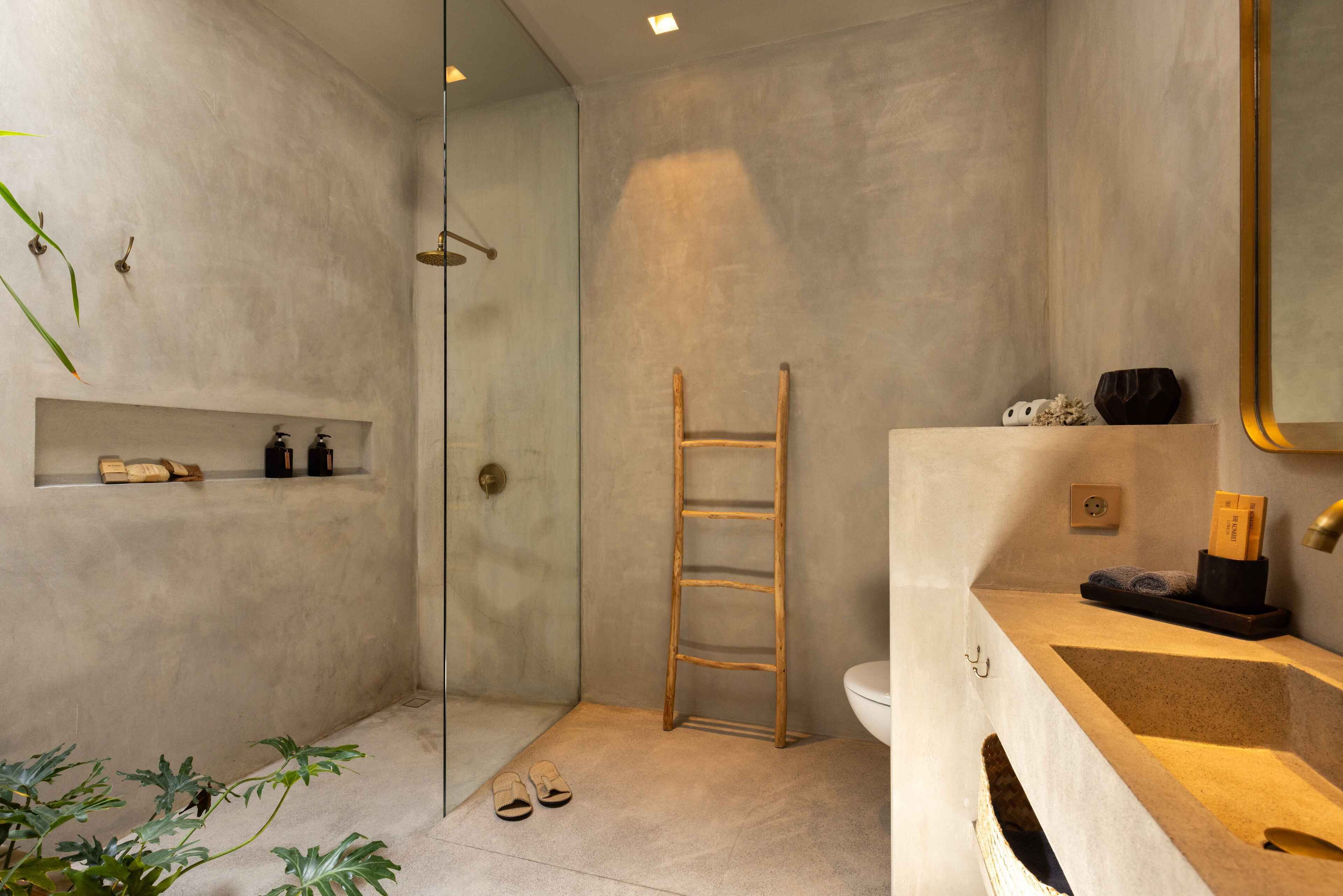 Une salle de bain moderne avec une douche à parois de verre, une échelle en bois, un lavabo avec un miroir et une étagère contenant des articles de toilette.