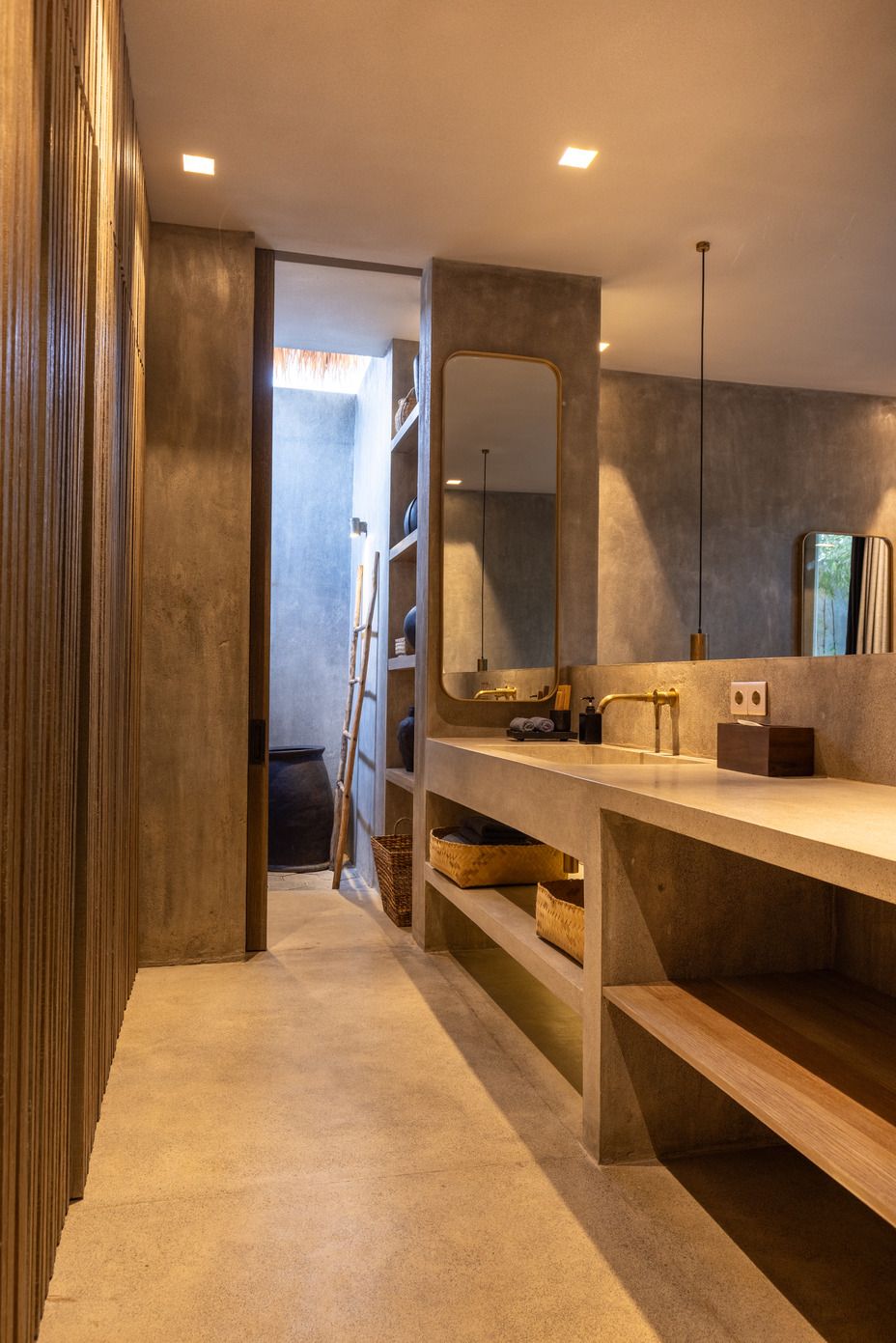 A modern bathroom with a large mirror, a wooden vanity, and a ladder leaning against the wall.