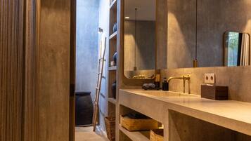 A modern bathroom with a large mirror, a wooden vanity, and a ladder leaning against the wall.