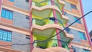 A multi-story building with balconies, a visible store sign, and a brick facade. - Lux Suites Trm drive Apartments Roysambu (Nairobi)