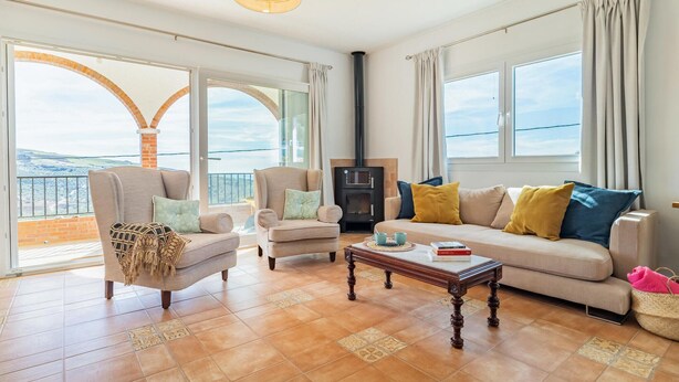 A spacious living room with a fireplace, two sofas, a coffee table, and large windows offering a view of the landscape. - Pet friendly home in Periana (Periana)