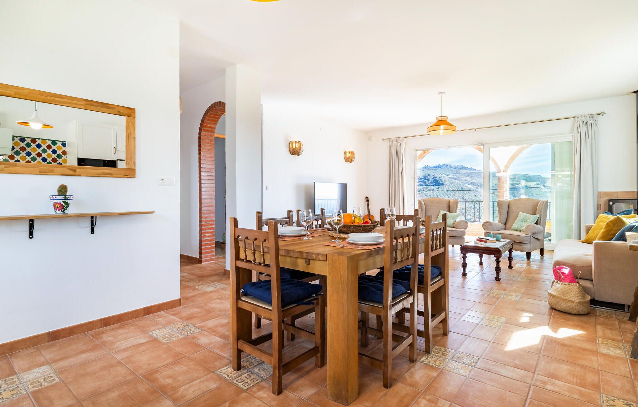 A dining area with a wooden table and chairs, a TV, and a view of the outdoors.