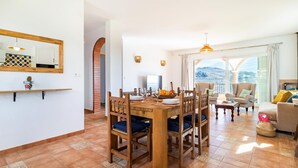 A dining area with a wooden table and chairs, a TV, and a view of the outdoors. - Pet friendly home in Periana (Periana)