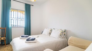 A bedroom with a bed, a chair, a window with curtains, and a bedside table. - Pet friendly home in Periana (Periana)