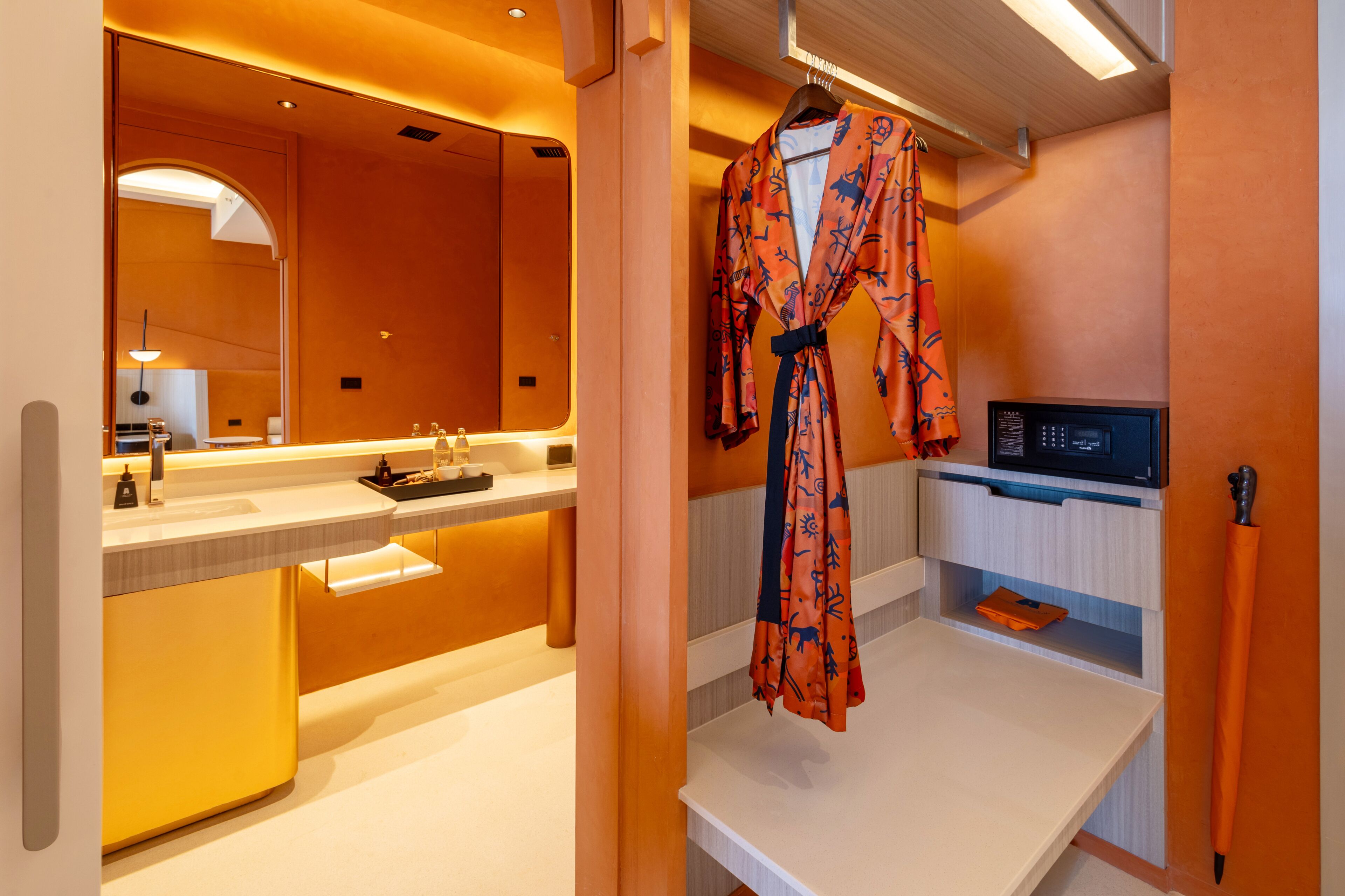 A modern bathroom with a large mirror, a sink, and a robe hanging on a rack.
