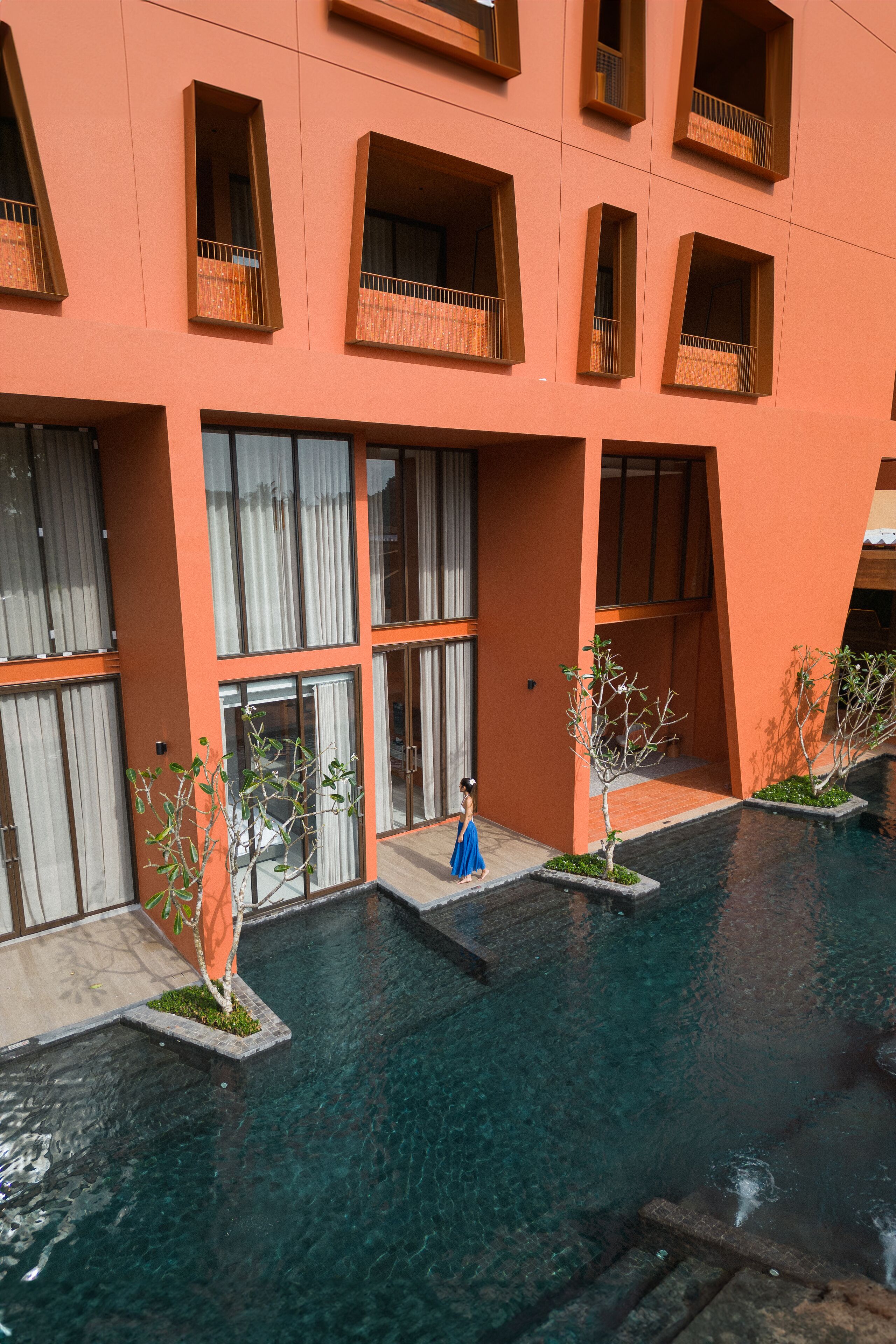 A modern building with multiple balconies and a central courtyard with a pool.