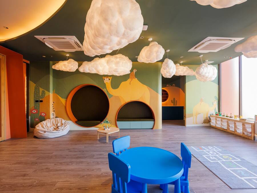 A children's playroom with a round table, blue chairs, and a large circular play area.